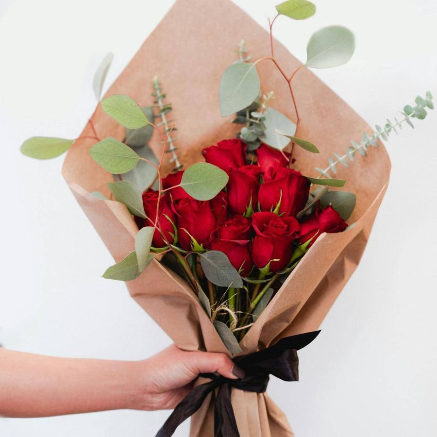 Ramo de rosas rojas envuelto en papel